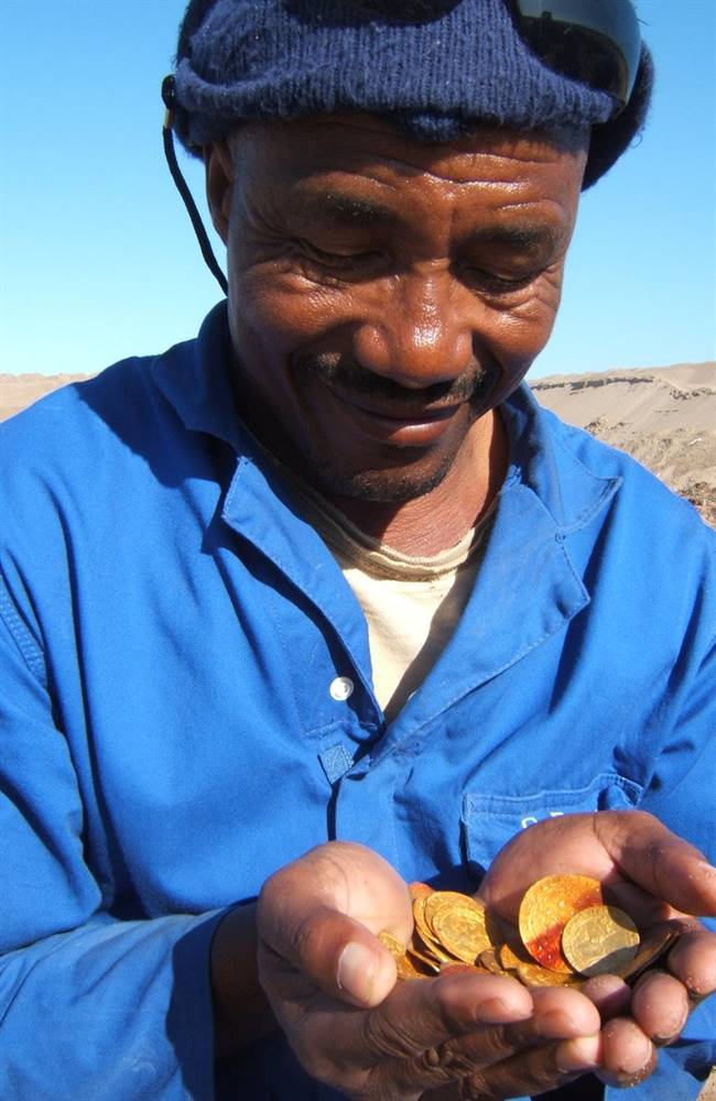 A mine worker with some of the coins found during the excavation. | Source: News.com.au/Dieter Noli