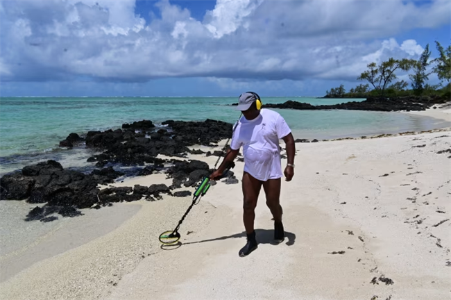Manguillier is often seen with a metal detector in hand, wearing distinctive bulbous yellow headphones.
